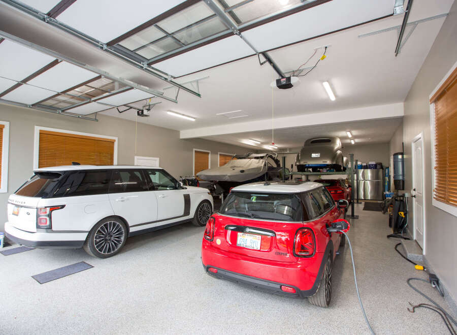 This spacious garage boasts ample room for multiple vehicles, including a sleek white SUV and a vibrant red Mini Cooper.