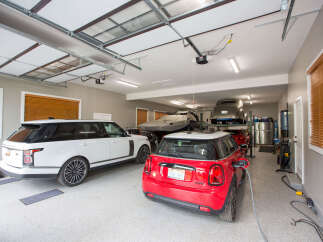 This spacious garage boasts ample room for multiple vehicles, including a sleek white SUV and a vibrant red Mini Cooper.
