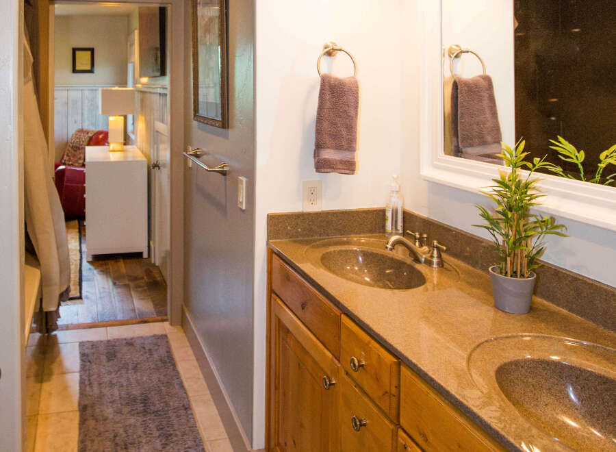 This beautiful bathroom features a double vanity with a stunning granite countertop and wooden cabinets.