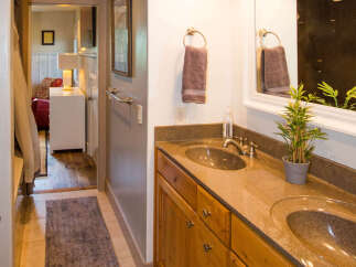 This beautiful bathroom features a double vanity with a stunning granite countertop and wooden cabinets.