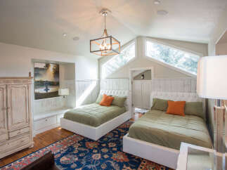 This charming bedroom features two cozy beds with plush bedding and vibrant orange accent pillows.