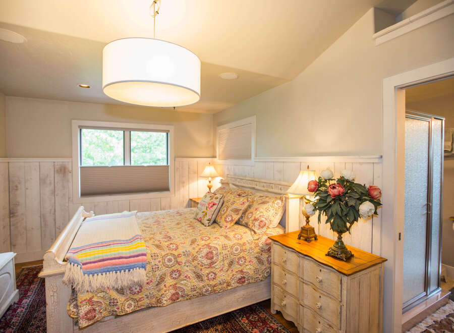 This charming bedroom features a cozy bed adorned with a colorful quilt and decorative pillows.