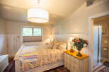 This charming bedroom features a cozy bed adorned with a colorful quilt and decorative pillows.