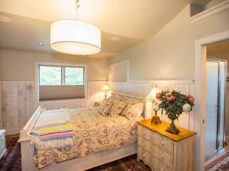 This charming bedroom features a cozy bed adorned with a colorful quilt and decorative pillows.