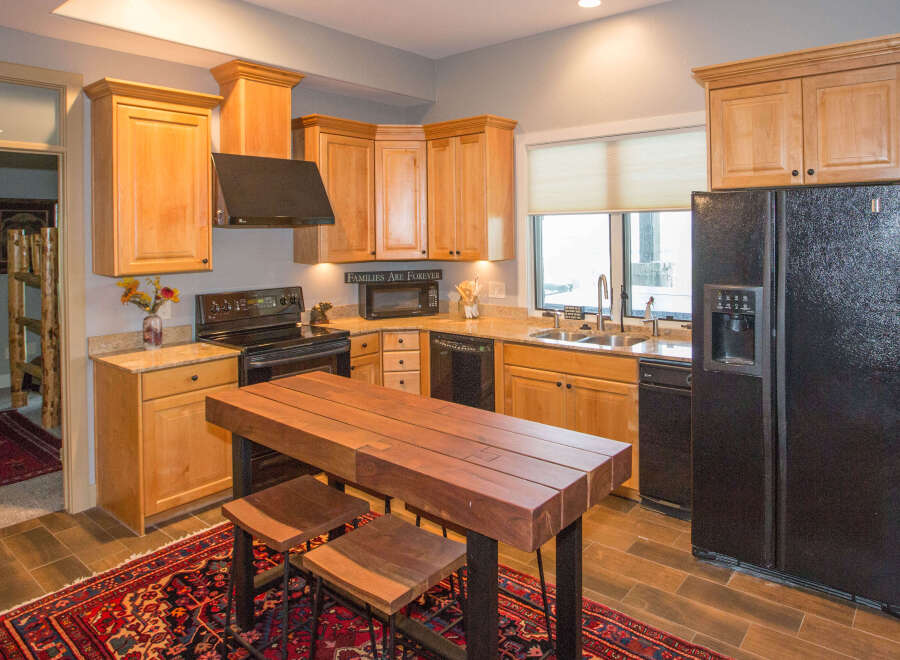 This stunning kitchen boasts beautiful wooden cabinetry and a sleek black appliance package.