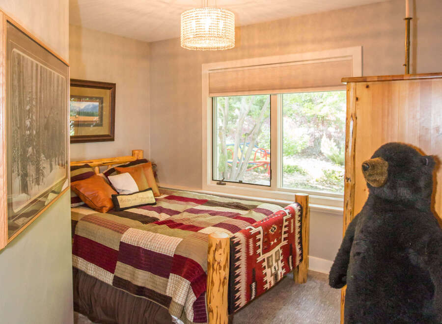 This cozy bedroom features a rustic log bed frame and a colorful quilt, creating a warm and inviting atmosphere.