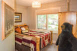 This cozy bedroom features a rustic log bed frame and a colorful quilt, creating a warm and inviting atmosphere.