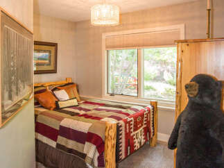 This cozy bedroom features a rustic log bed frame and a colorful quilt, creating a warm and inviting atmosphere.