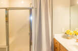This bathroom features a modern shower with a glass door and a neutral-toned curtain for privacy.