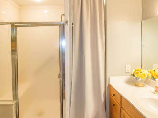 This bathroom features a modern shower with a glass door and a neutral-toned curtain for privacy.