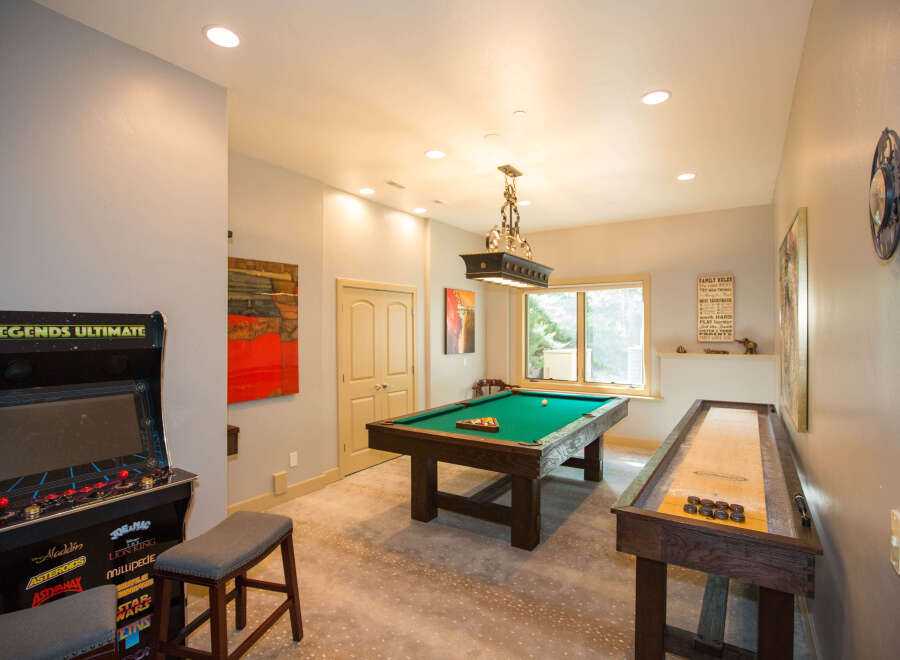 This stunning game room features a Legends Ultimate arcade game, a pool table, and a shuffleboard, offering endless entertainment options.