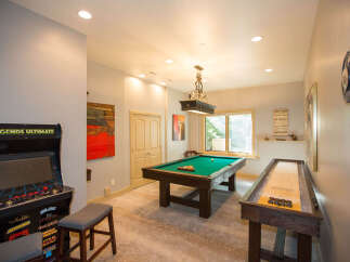 This stunning game room features a Legends Ultimate arcade game, a pool table, and a shuffleboard, offering endless entertainment options.