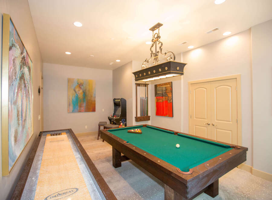 This game room features a pool table, shuffleboard, and arcade game, perfect for entertaining guests.