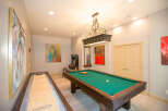 This game room features a pool table, shuffleboard, and arcade game, perfect for entertaining guests.