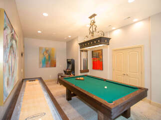 This game room features a pool table, shuffleboard, and arcade game, perfect for entertaining guests.