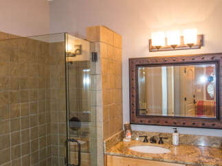 This bathroom features a stylish chandelier and a modern glass shower.