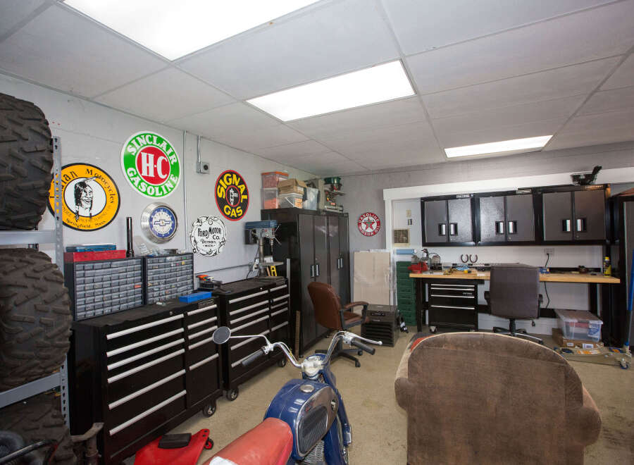 This garage is a haven for any car enthusiast, featuring a vintage motorcycle and a collection of classic signs.