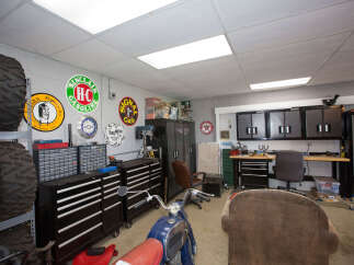 This garage is a haven for any car enthusiast, featuring a vintage motorcycle and a collection of classic signs.