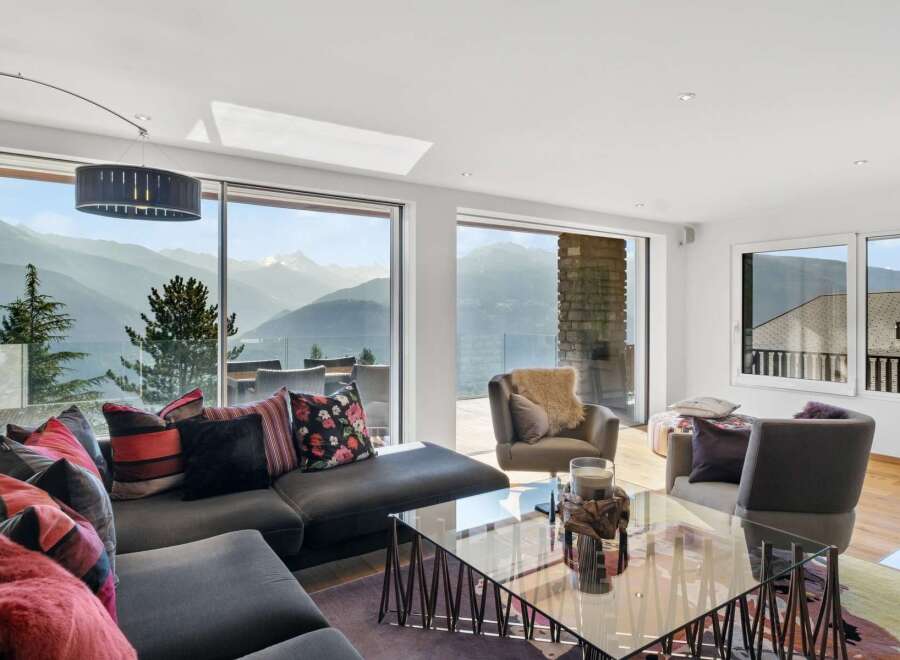This luxurious living room boasts breathtaking panoramic mountain views through expansive floor-to-ceiling windows.