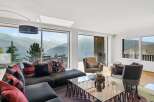 This luxurious living room boasts breathtaking panoramic mountain views through expansive floor-to-ceiling windows.