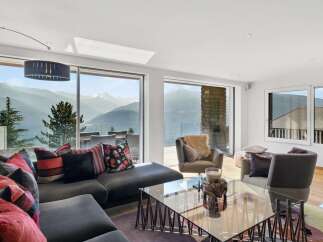 This luxurious living room boasts breathtaking panoramic mountain views through expansive floor-to-ceiling windows.
