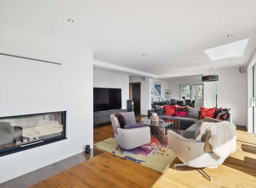 This stunning living room boasts a sleek, modern design with hardwood floors, a contemporary fireplace, and large windows offering abundant natural light.