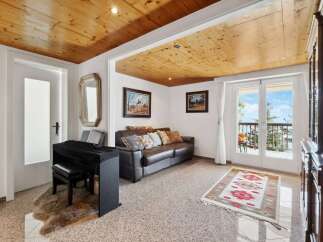 This stunning property boasts a spacious living area with a leather sofa, hardwood floors, and large windows offering breathtaking views.