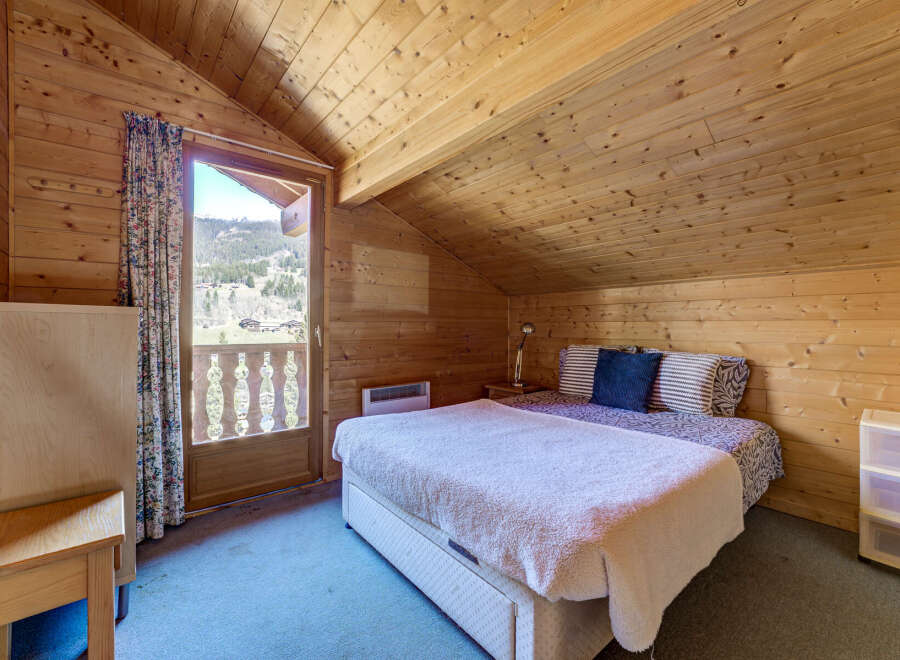 Cozy bedroom with wooden walls and ceiling, creating a warm and inviting atmosphere.