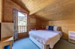 Cozy bedroom with wooden walls and ceiling, creating a warm and inviting atmosphere.