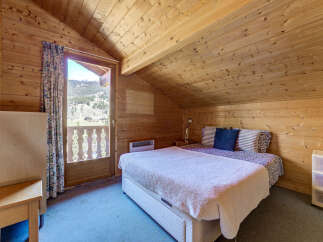Cozy bedroom with wooden walls and ceiling, creating a warm and inviting atmosphere.