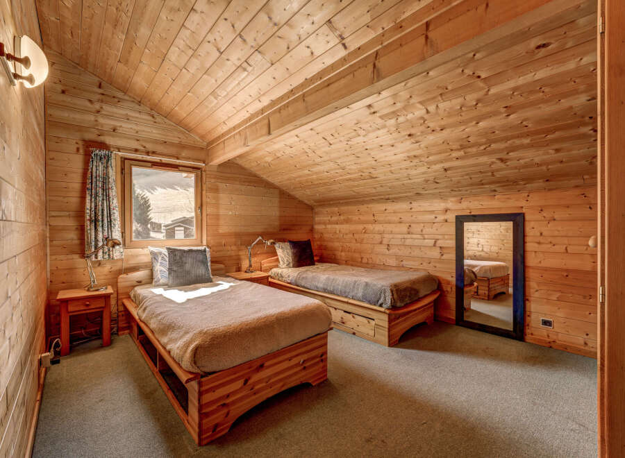 Cozy cabin bedroom with wooden walls and ceiling.