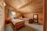 Cozy cabin bedroom with wooden walls and ceiling.