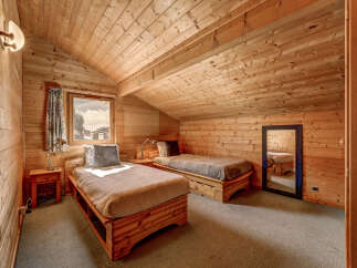 Cozy cabin bedroom with wooden walls and ceiling.