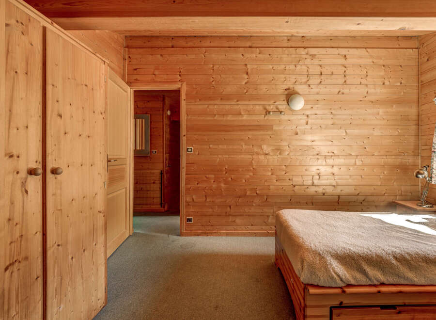 Step into a cozy bedroom retreat, featuring warm wooden paneling that envelops the space.