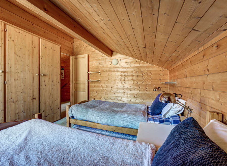 Cozy bedroom with wooden walls and ceiling, creating a warm and inviting atmosphere.