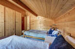Cozy bedroom with wooden walls and ceiling, creating a warm and inviting atmosphere.