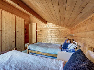 Cozy bedroom with wooden walls and ceiling, creating a warm and inviting atmosphere.