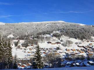 Experience the charm of a winter wonderland in this picturesque village nestled amidst snow-covered mountains.