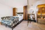 Experience luxury in this stunning hotel room featuring a cozy floral sofa and a comfortable bed.