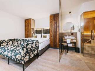 Experience luxury in this stunning hotel room featuring a cozy floral sofa and a comfortable bed.