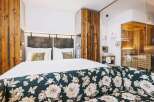 Experience luxury in this stunning hotel room, featuring a cozy bed and a beautifully designed floral sofa.