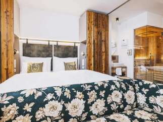 Experience luxury in this stunning hotel room, featuring a cozy bed and a beautifully designed floral sofa.