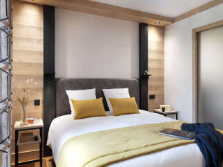This cozy bedroom features a comfortable double bed with a mustard yellow throw, complemented by a dark blue knitted blanket.