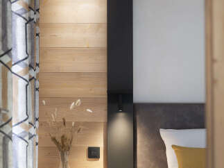 Cozy bedroom with wooden walls and a modern black accent wall.