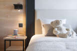 Cozy bedroom with wooden walls and a plush teddy bear on the bed.