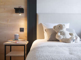 Cozy bedroom with wooden walls and a plush teddy bear on the bed.