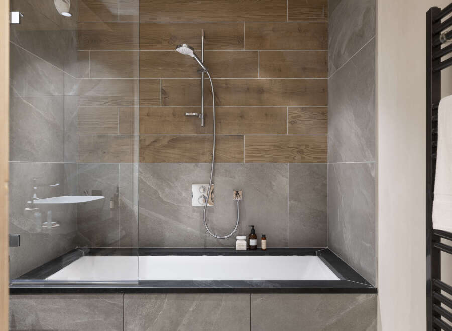 Modern bathroom with a sleek, built-in bathtub and a walk-in shower featuring a rainfall shower head.