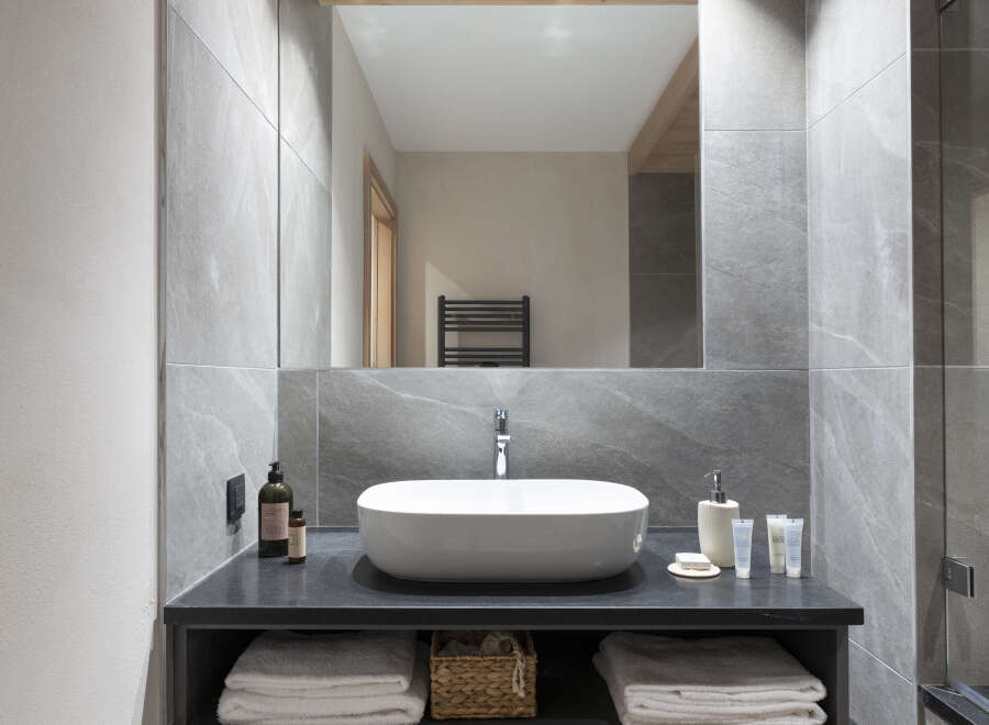 This modern bathroom boasts a sleek, minimalist design with a large rectangular sink and a spacious vanity featuring a light wood drawer.