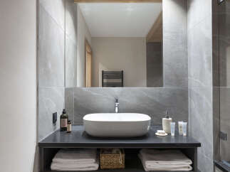 This modern bathroom boasts a sleek, minimalist design with a large rectangular sink and a spacious vanity featuring a light wood drawer.