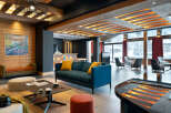 This stunning hotel lobby boasts a cozy and sophisticated atmosphere, featuring a teal sofa with yellow throw pillows, a modern coffee table, and a sleek black piano.